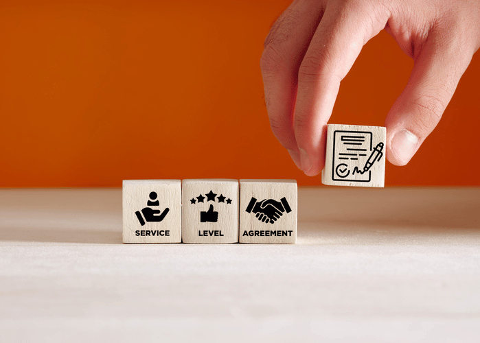 A hand places a wooden block with a document and pen icon next to blocks labeled 